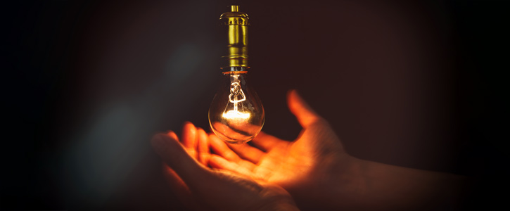 Hands cradling a light bulb