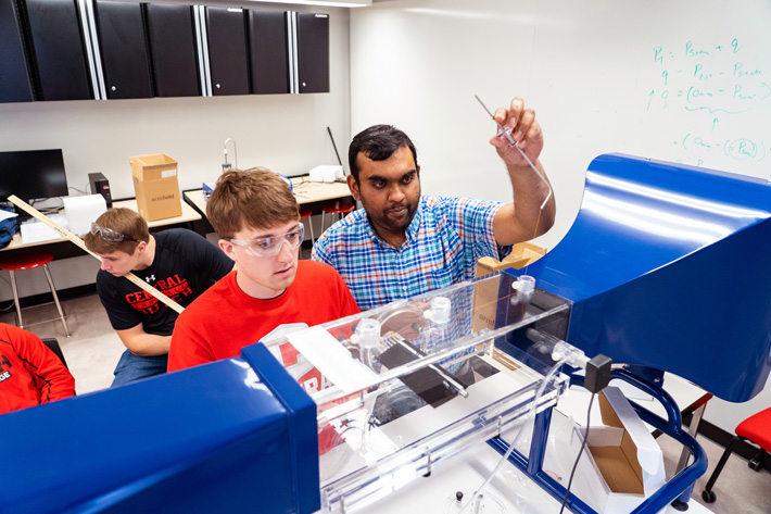 Central College students collaborating with a professor in the campus engineering lab.